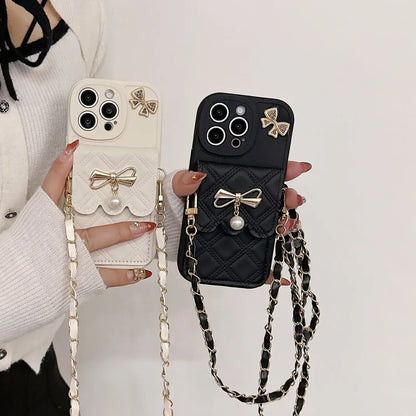 Two phone cases with bow designs and chains held by a person against a white background.
