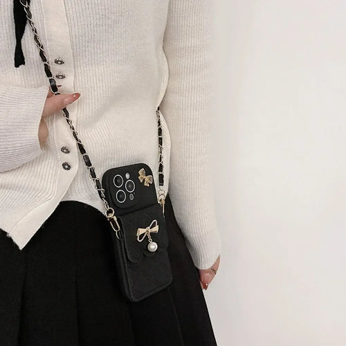 Person wearing a white sweater with a black phone case and chain accessory.
