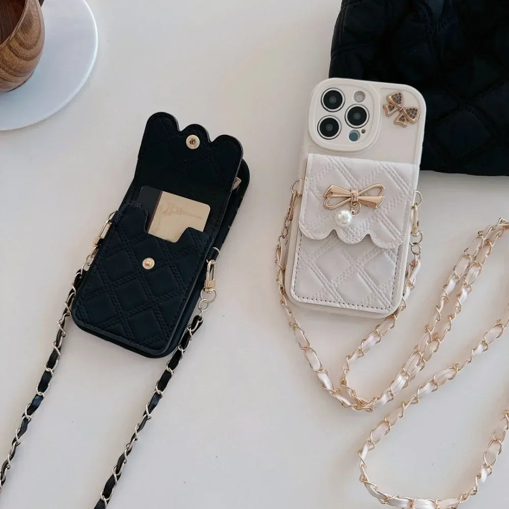 Two phone cases, one black and one white with a chain, on a light surface.
