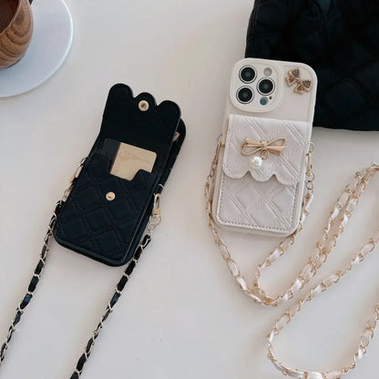 Two phone cases, one black and one white with a chain, on a light surface.