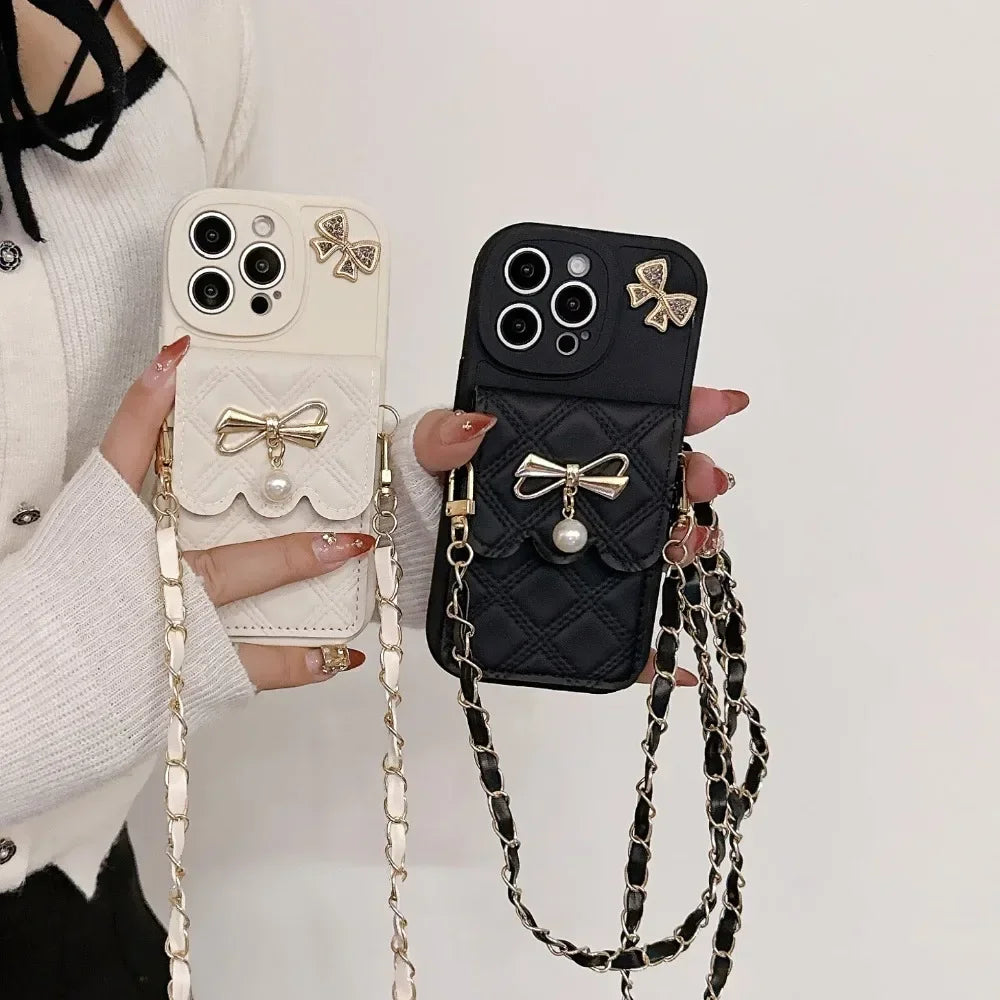 Two phone cases with bow designs and chain straps held by a person.