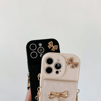 Two quilted phone cases with bow embellishments, one black and one cream, held in a hand against a plain light background.